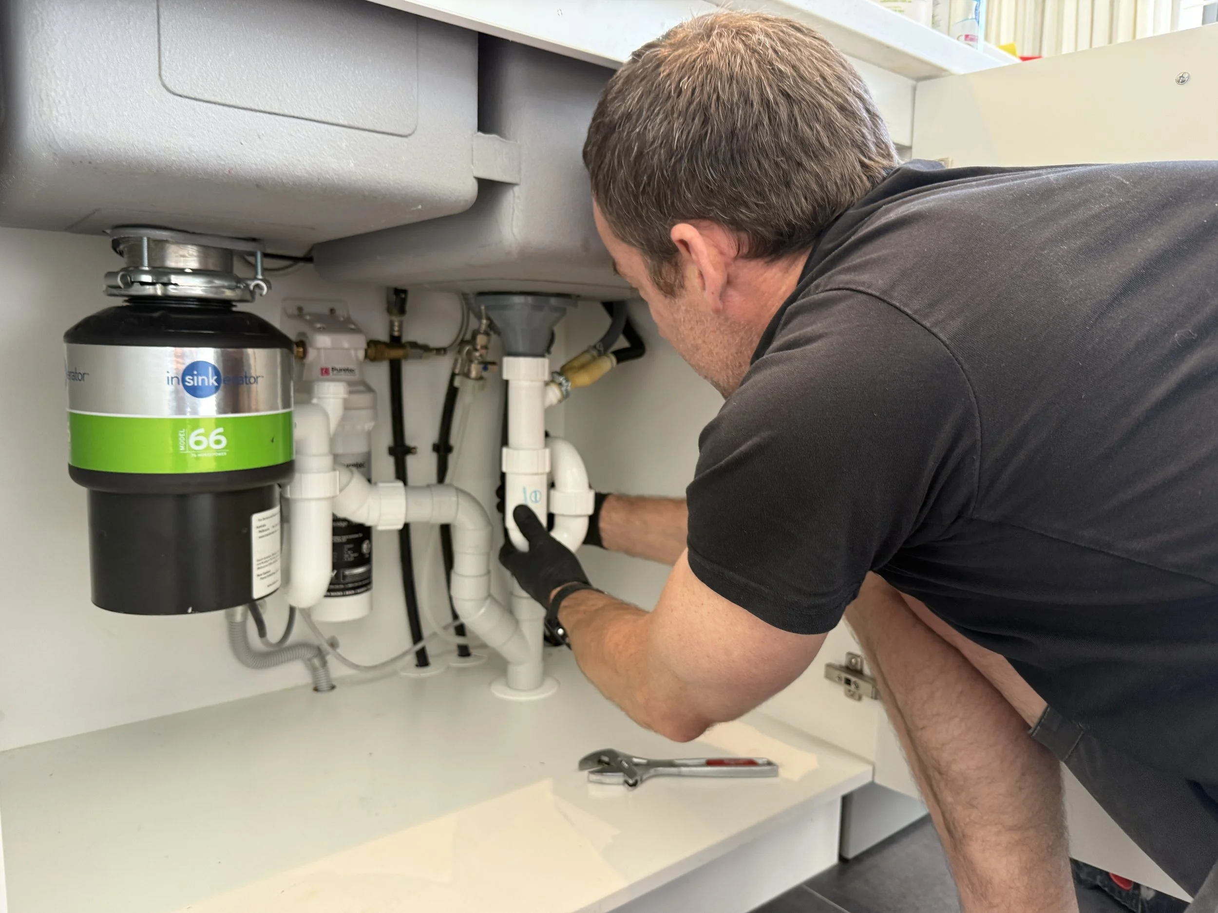 plumber-servicing-pipes-under-sink