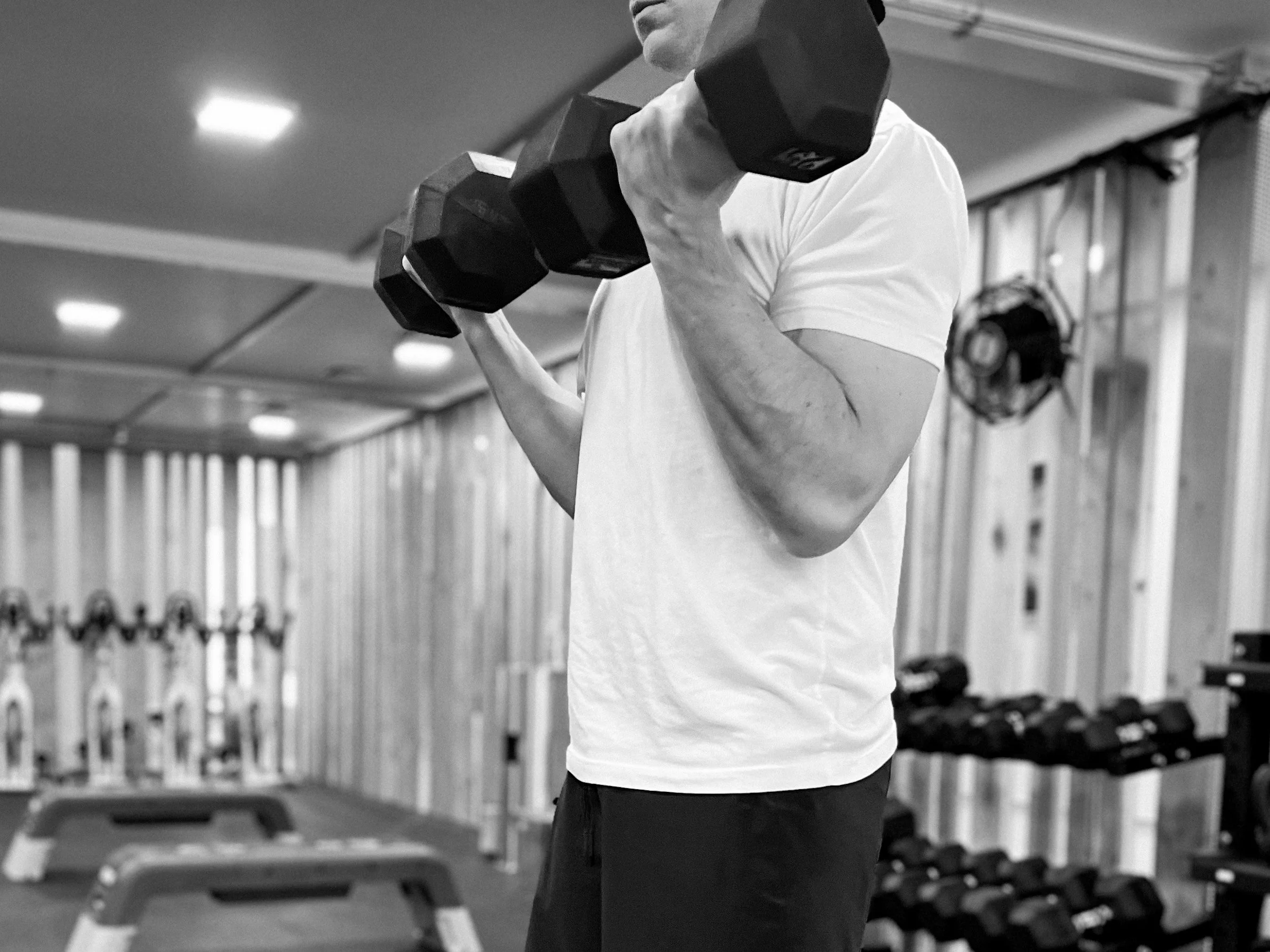 A man lifting a dumbbell in a gym.