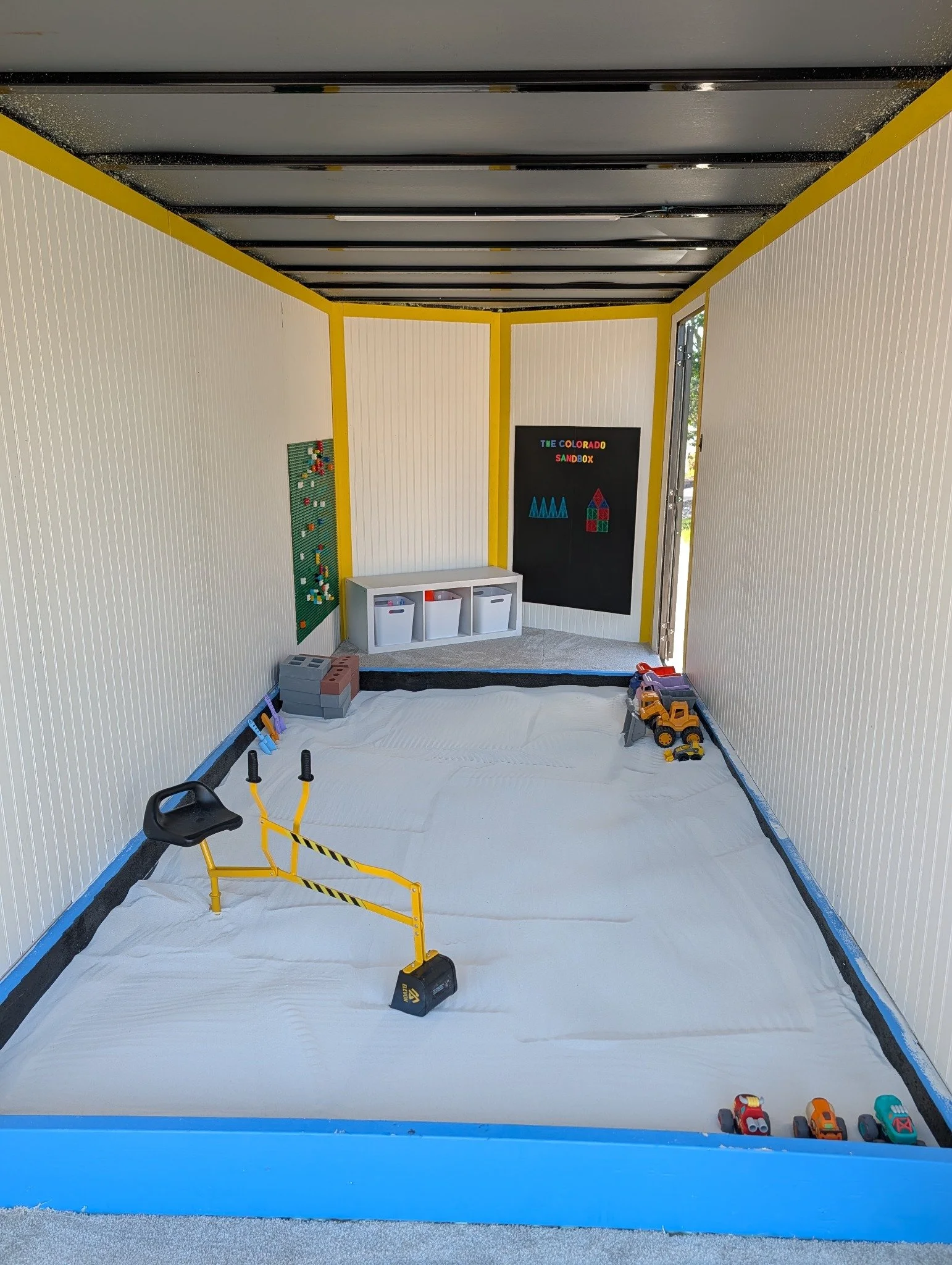 Construction-themed sandbox and play walls inside the trailer