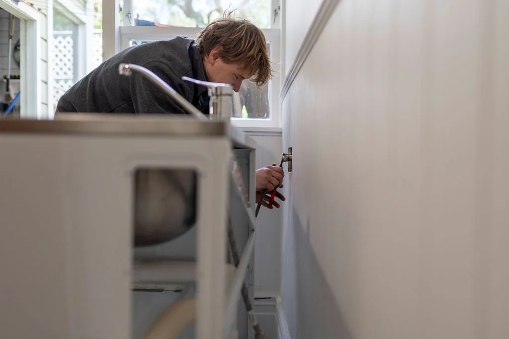 A person fixing a cabinet door in a kitchen during daytime.