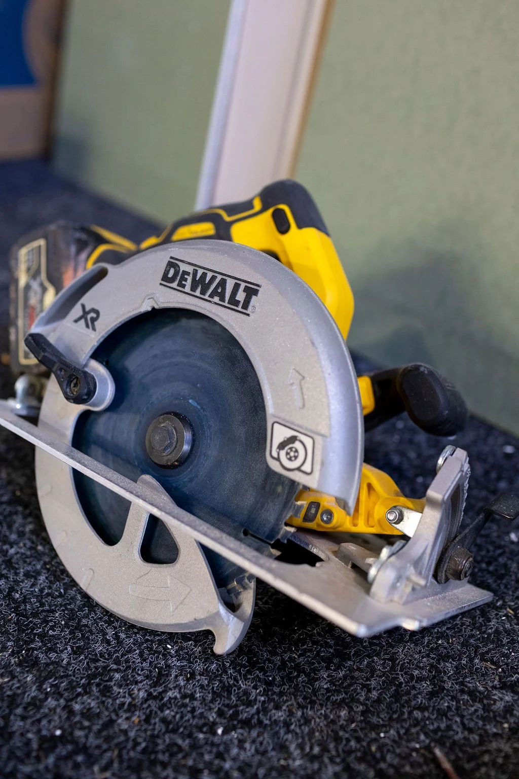 Close-up of a DeWalt circular saw with a yellow and black handle, placed on a dark textured surface.