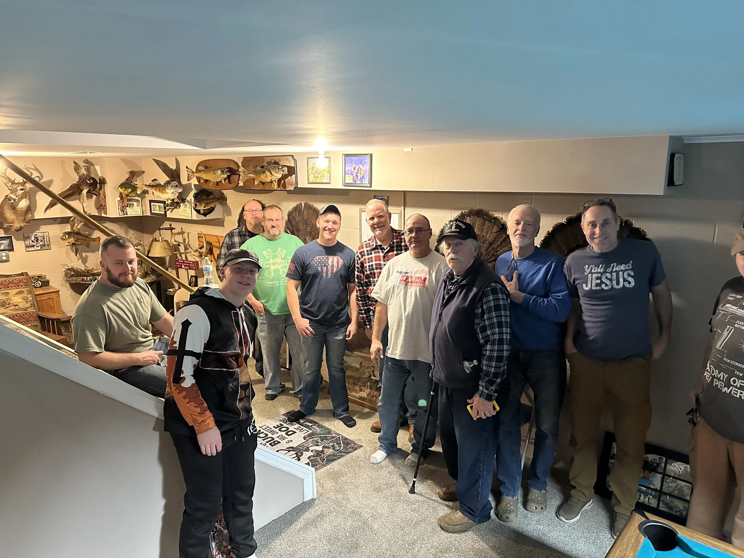 Group of men standing inside a room decorated with mounted fish and wildlife displays.