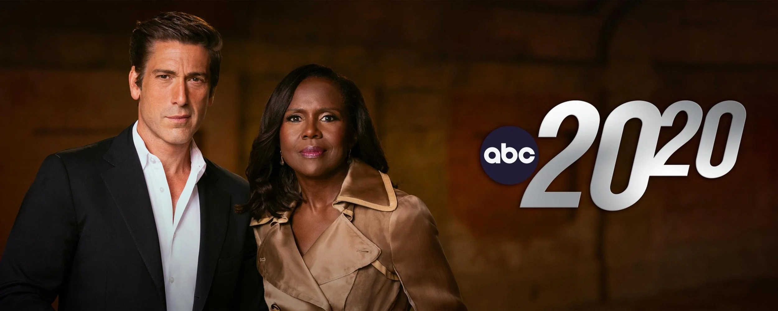 Two characters from the TV show "gray's Anatomy" standing together, man in a black suit with white shirt and woman in a beige trench coat, with "abc 20/20" logo in the background.