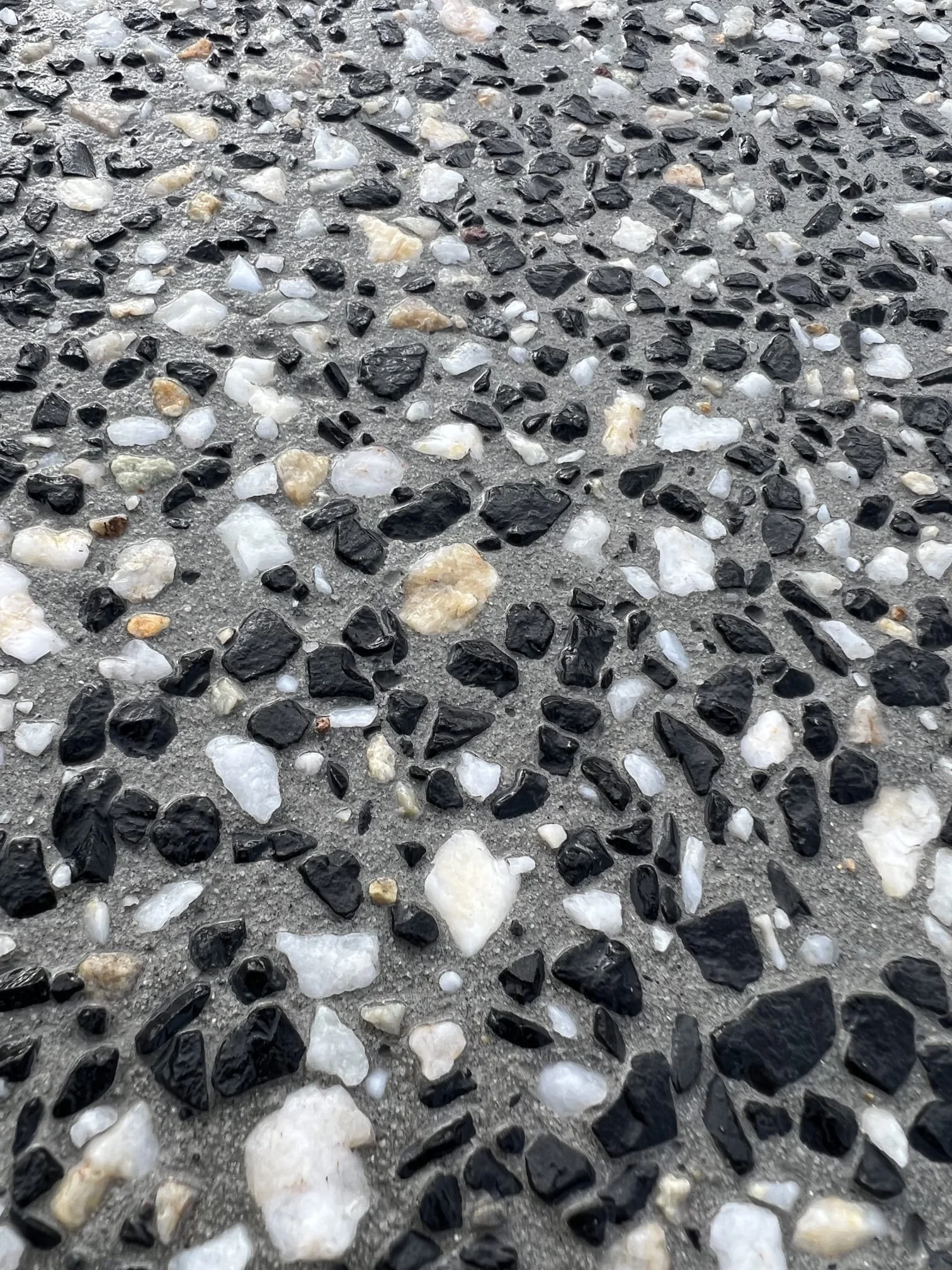 Close-up of textured concrete surface embedded with small black, white, and beige stones.