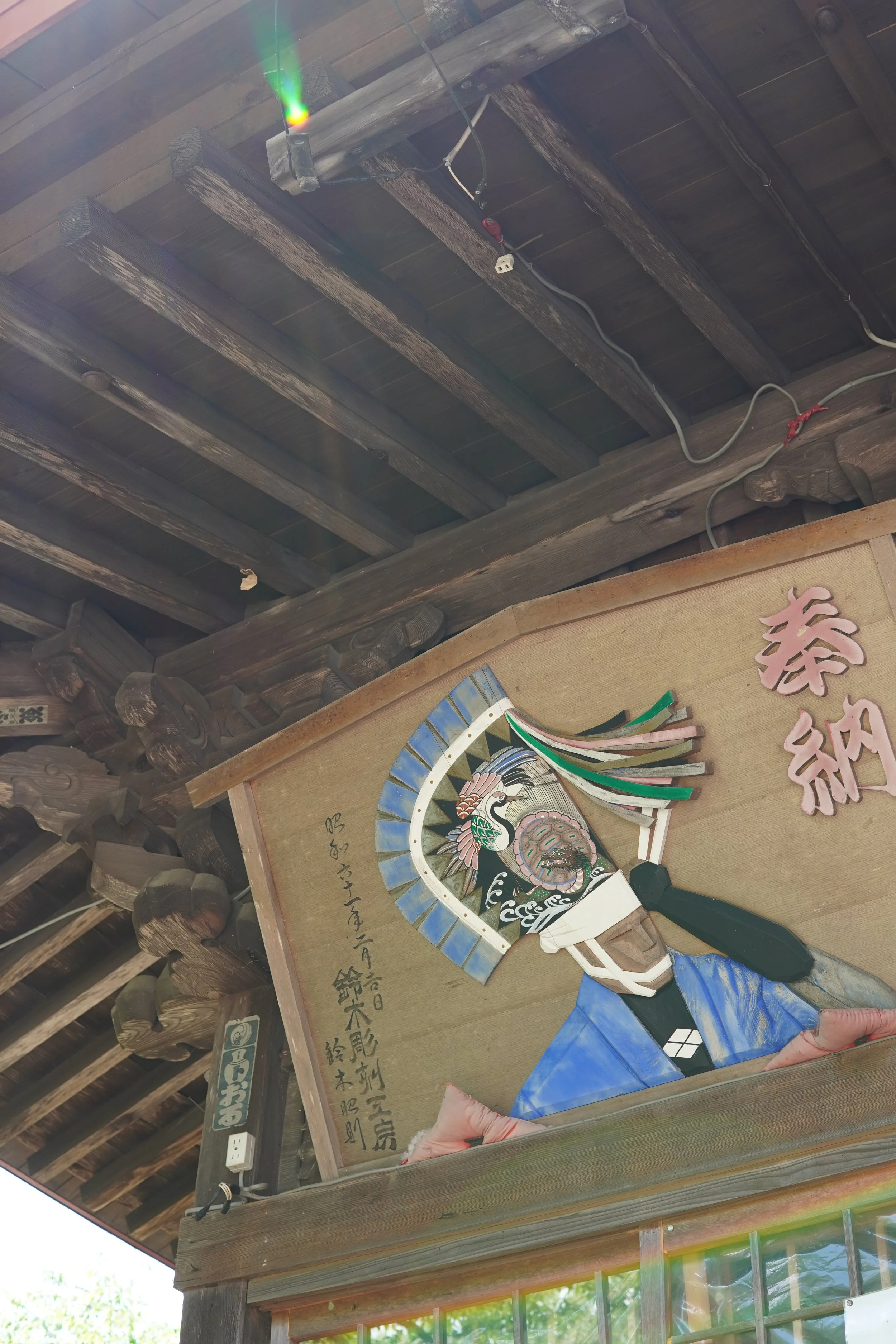 伝統的な筆や和紙と、日本語の書かれた板が飾られている木の建物の内部の写真