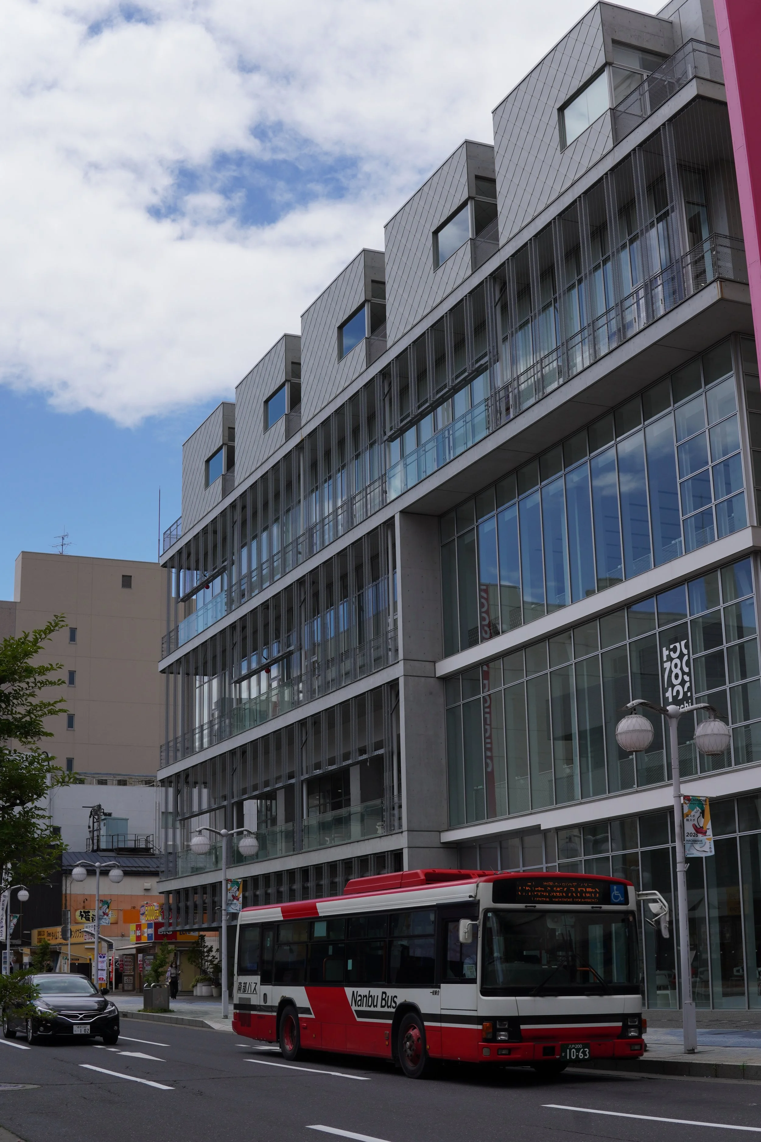都市の通りに止まっているバスと車、背景に高層ビルと空。