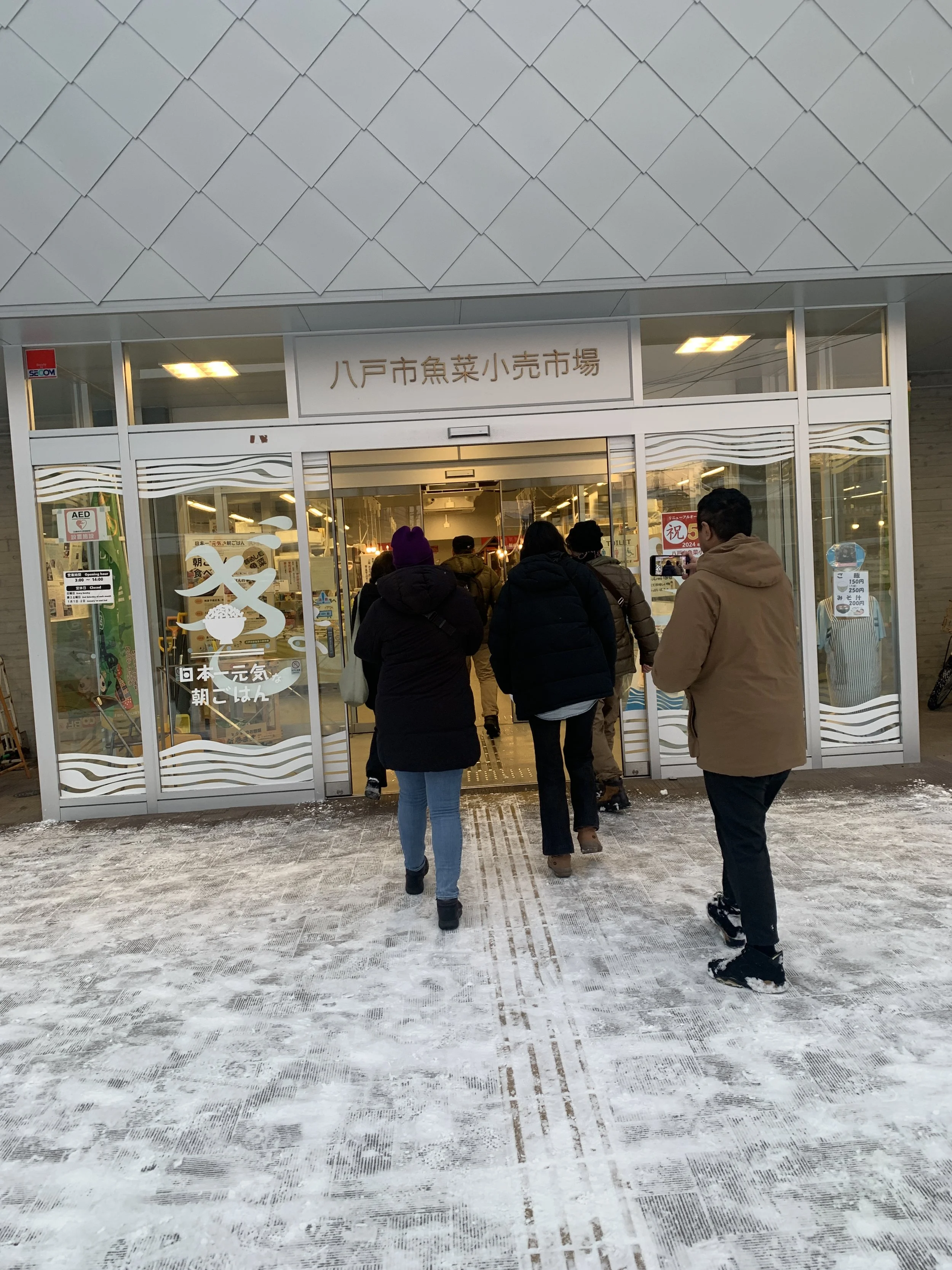 八戸市魚菜小売市場入口に入る人々