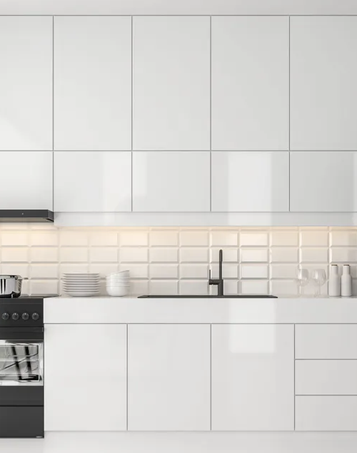 Modern white kitchen with upper and lower cabinets, a black stove, a sink with a faucet, a tiled backsplash, and some dishes.