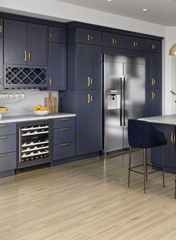 Modern kitchen with navy blue cabinets, stainless steel refrigerator, wine storage, and a wood countertop with fruit bowls and a cutting board.