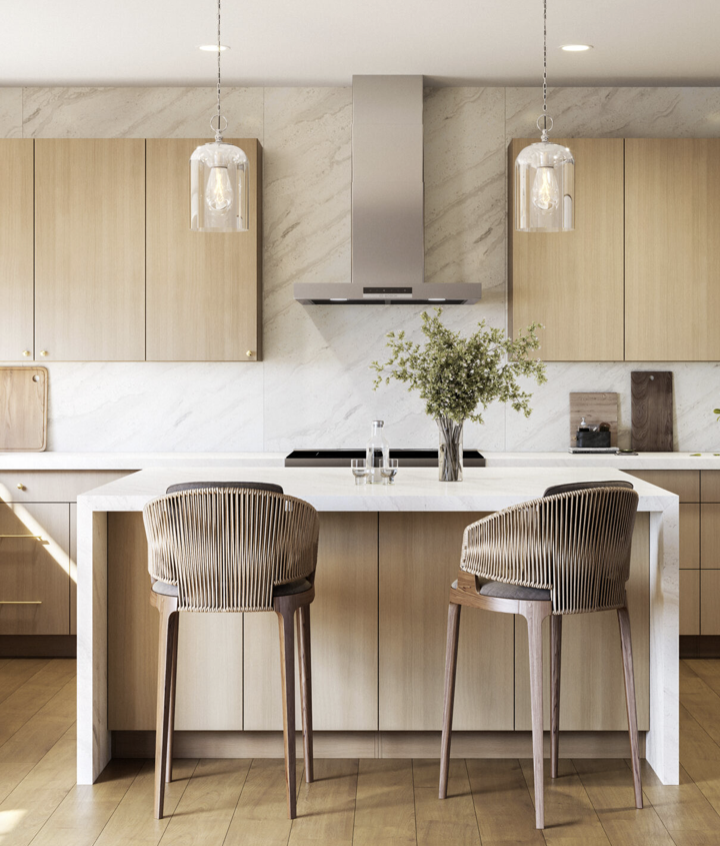 Modern kitchen with a white island, light wood cabinets, two wicker barstools, a vase with greenery, and pendant lights.