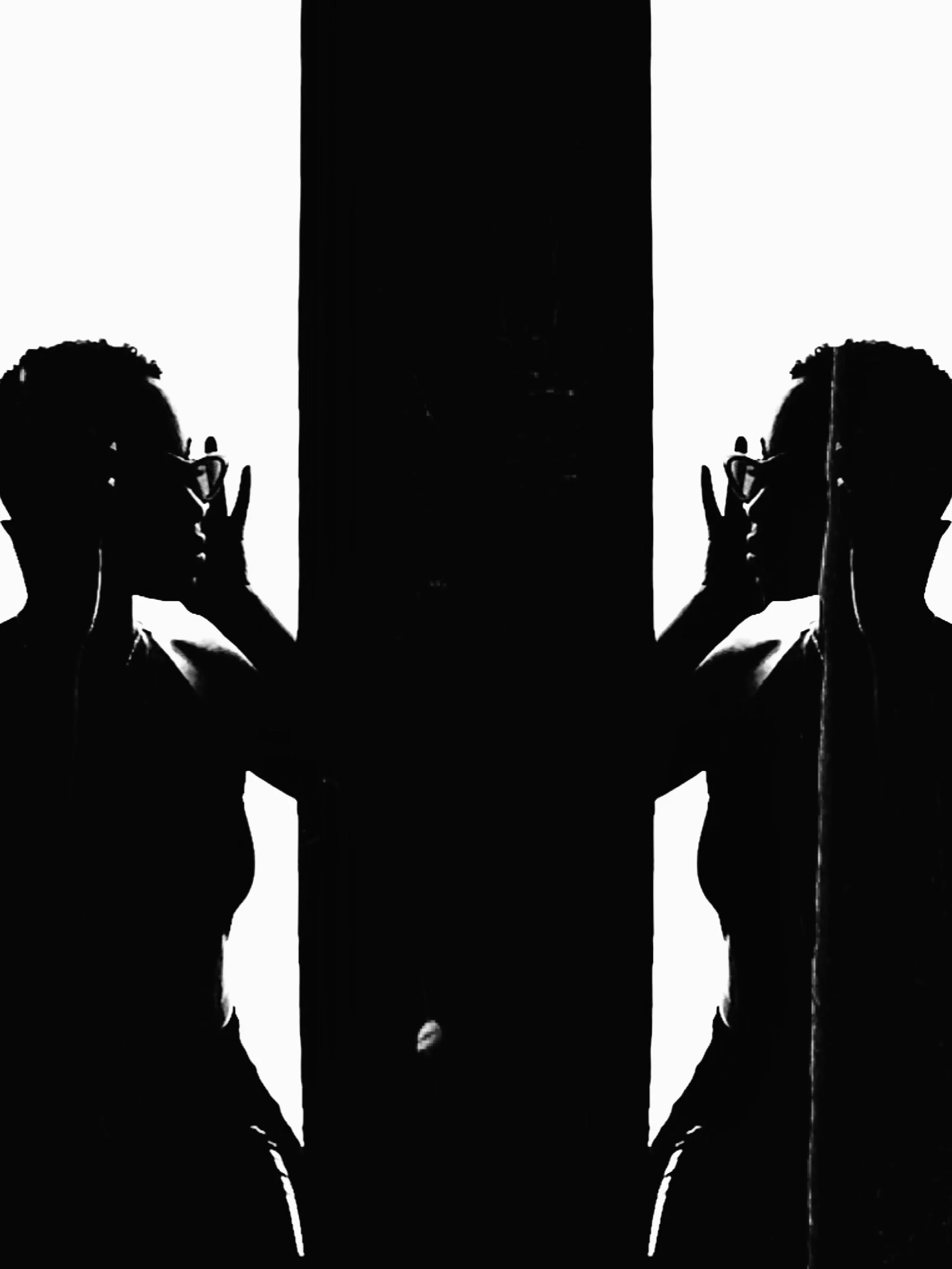 Black and white mirrored image of a person wearing glasses, holding a phone to their ear on each side.