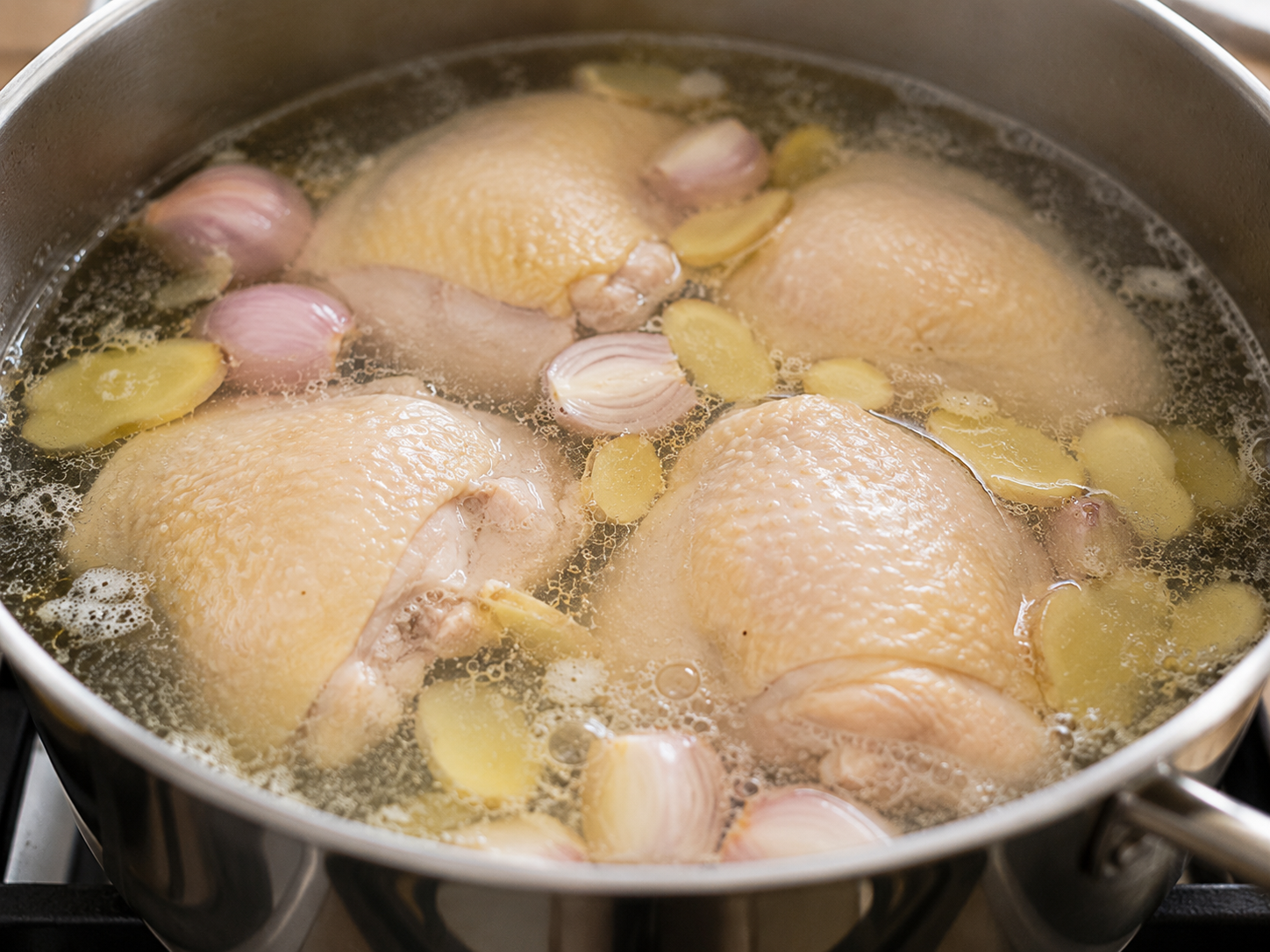 Chicken thighs gently poaching with ginger and shallots for gỏi gà bắp cải.
