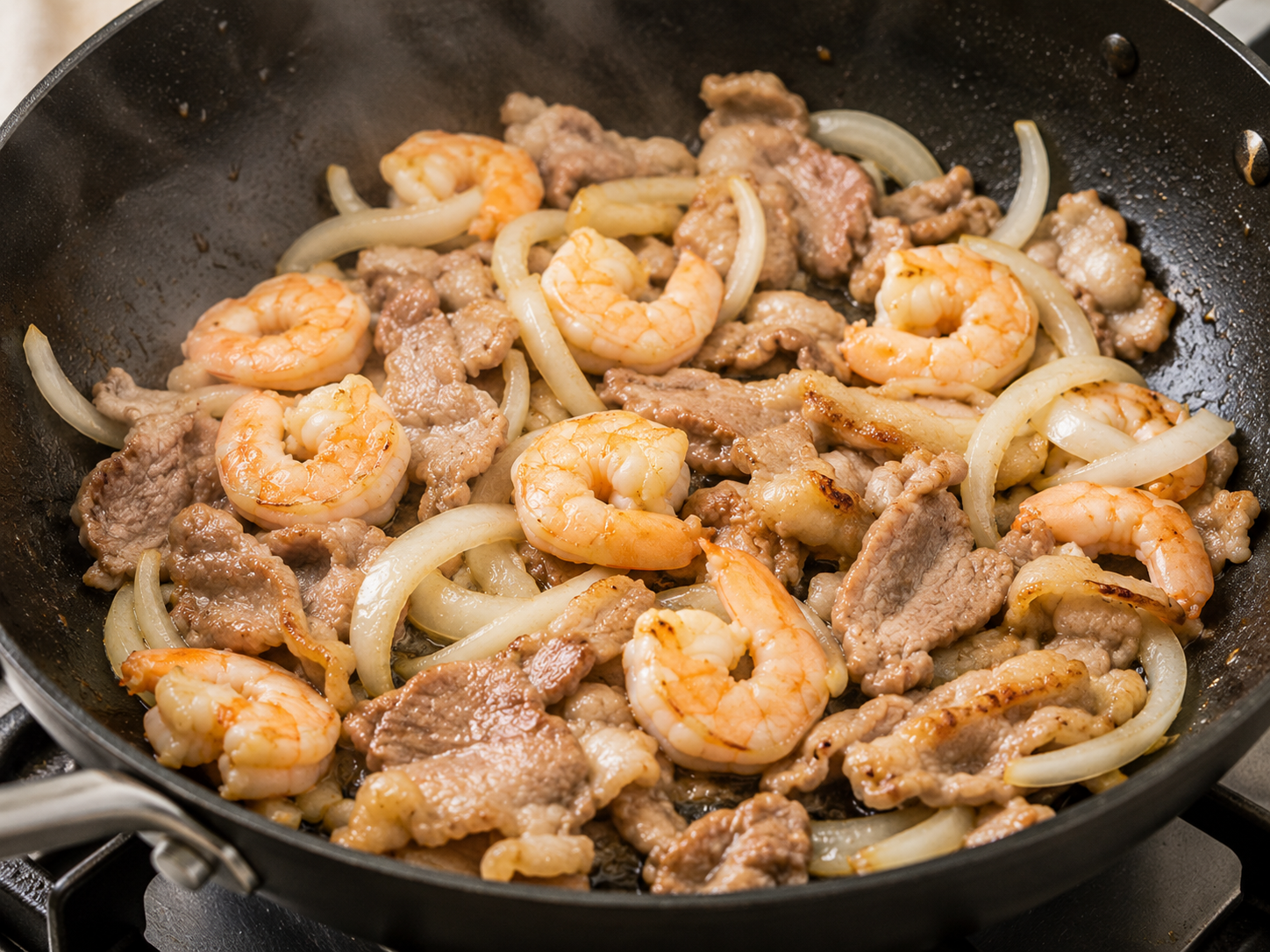 Shrimp, thinly sliced pork, and onions cooking in a skillet for bánh xèo filling.