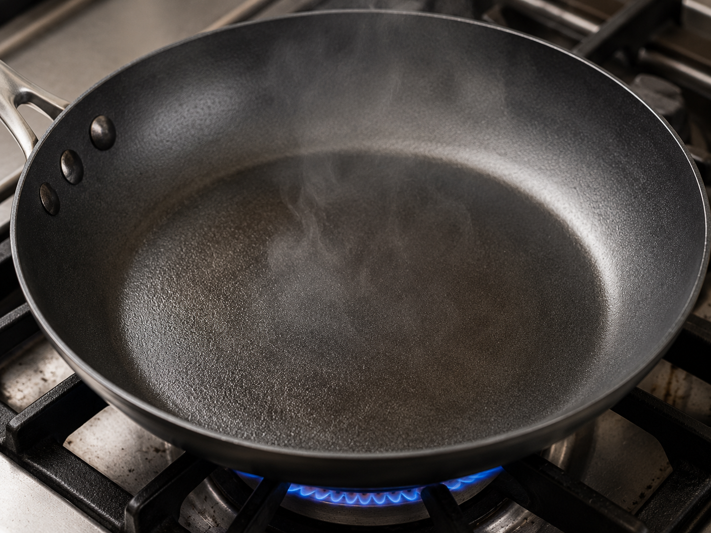 A hot skillet heating over a gas flame for cooking bánh xèo until the pan is properly hot before adding oil and batter.
