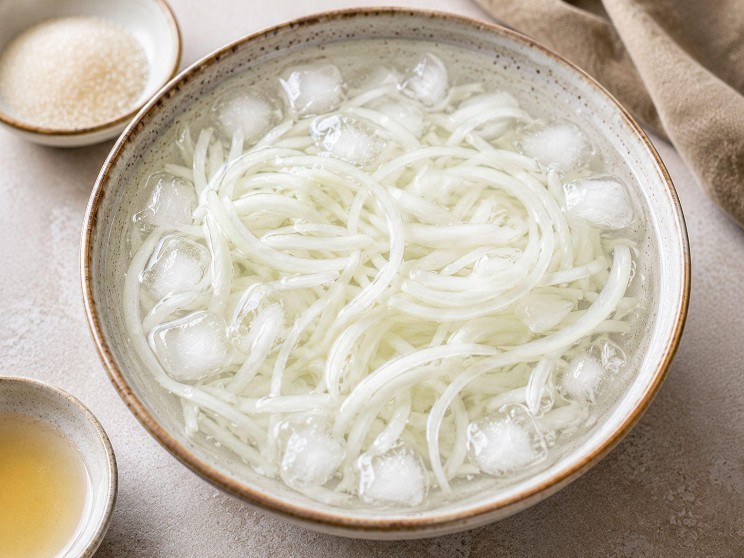Thinly sliced onion soaking in ice water with vinegar and sugar for gỏi gà bắp cải.