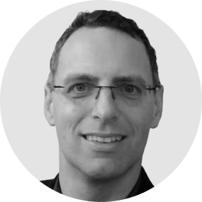 Portrait of a man with glasses smiling at the camera, black and white photo.