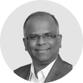 Portrait of a smiling man with glasses wearing a suit jacket and white shirt