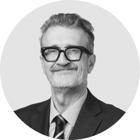 Black and white portrait of a smiling man with glasses, wearing a suit and tie.