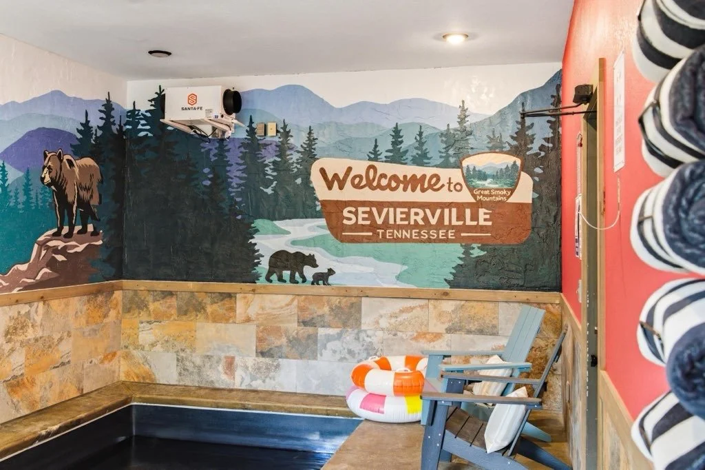 Custom hand-painted mountain mural featuring the Sevierville, Tennessee welcome sign with scenic Smoky Mountain landscape, wildlife, and forest artwork created by Blush Pony Studio.