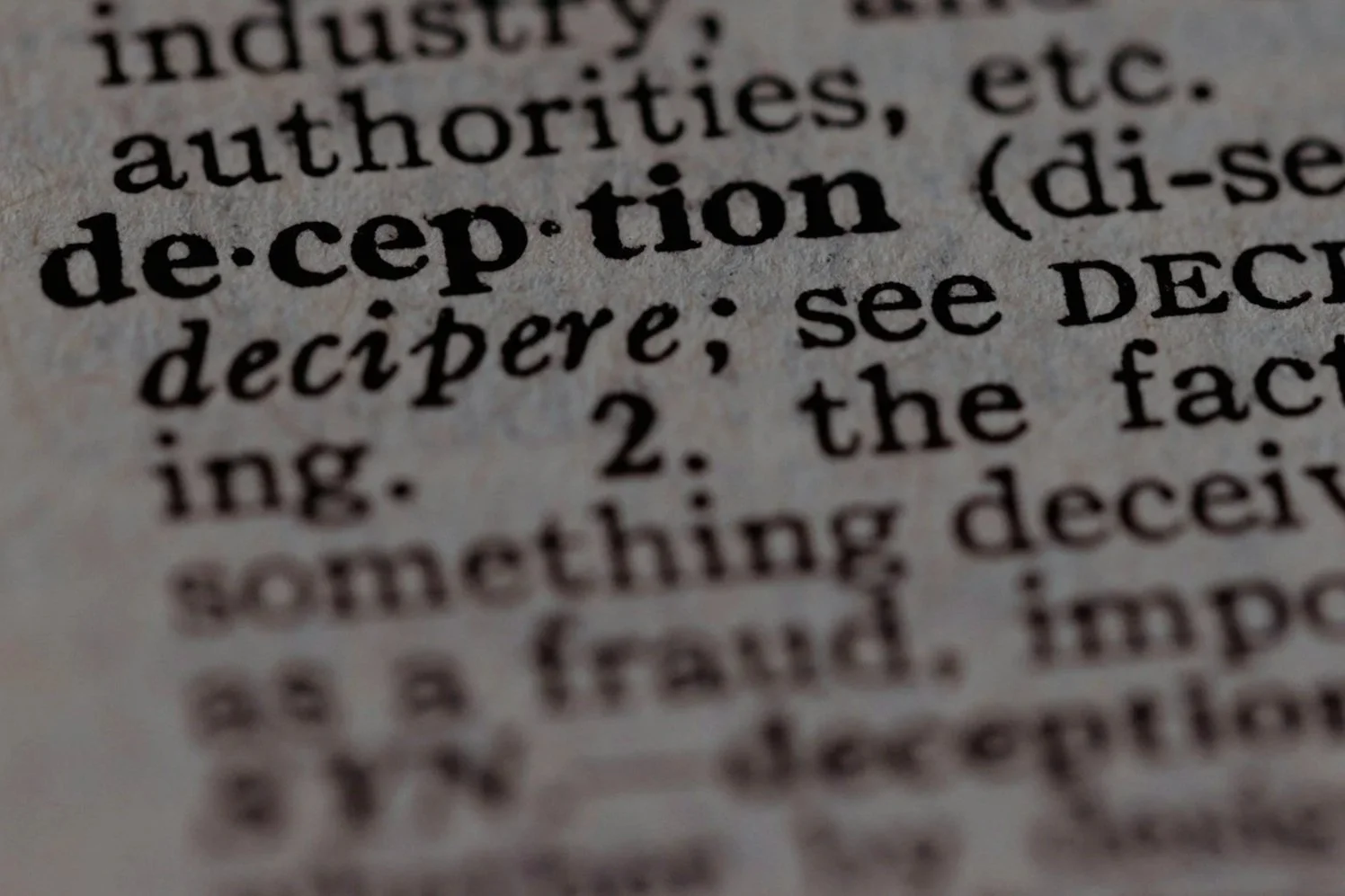 Close-up of dictionary entry for the word "deception" showing its pronunciation and definition.