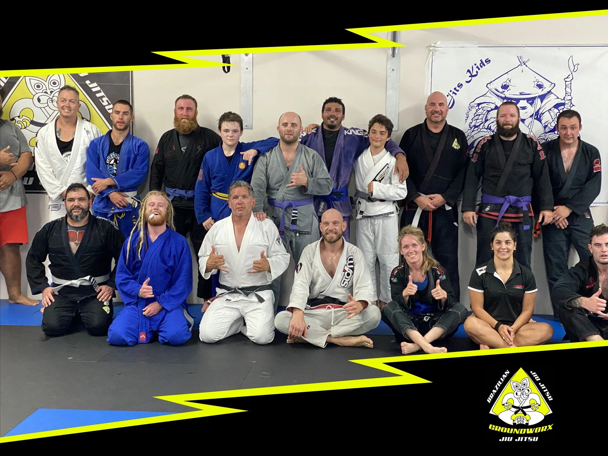 Group of people in Brazilian Jiu Jitsu uniforms posing together in a martial arts dojo.