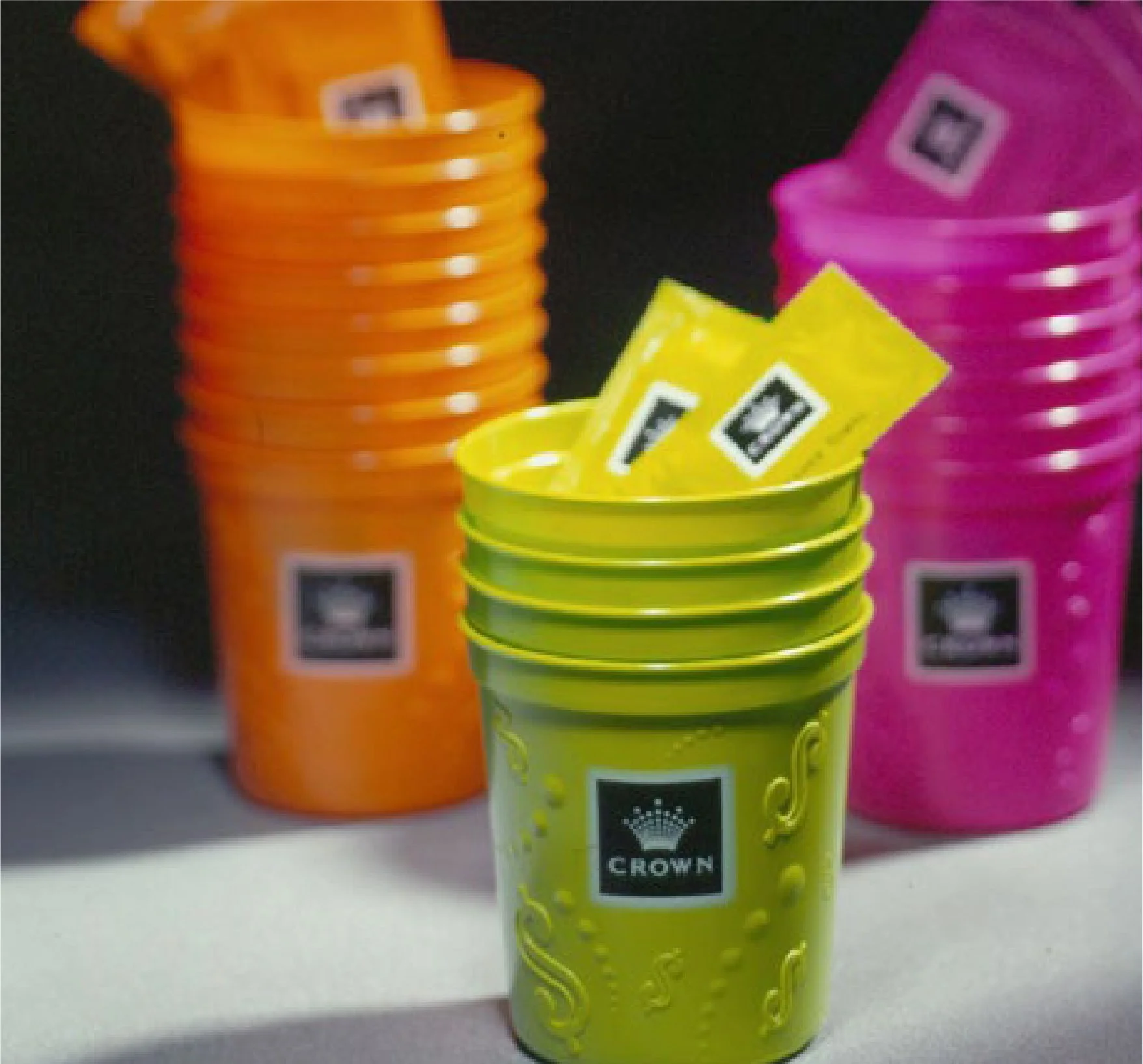 Colorful buckets with some with unopened packs of playing cards inside, on a black and white surface.