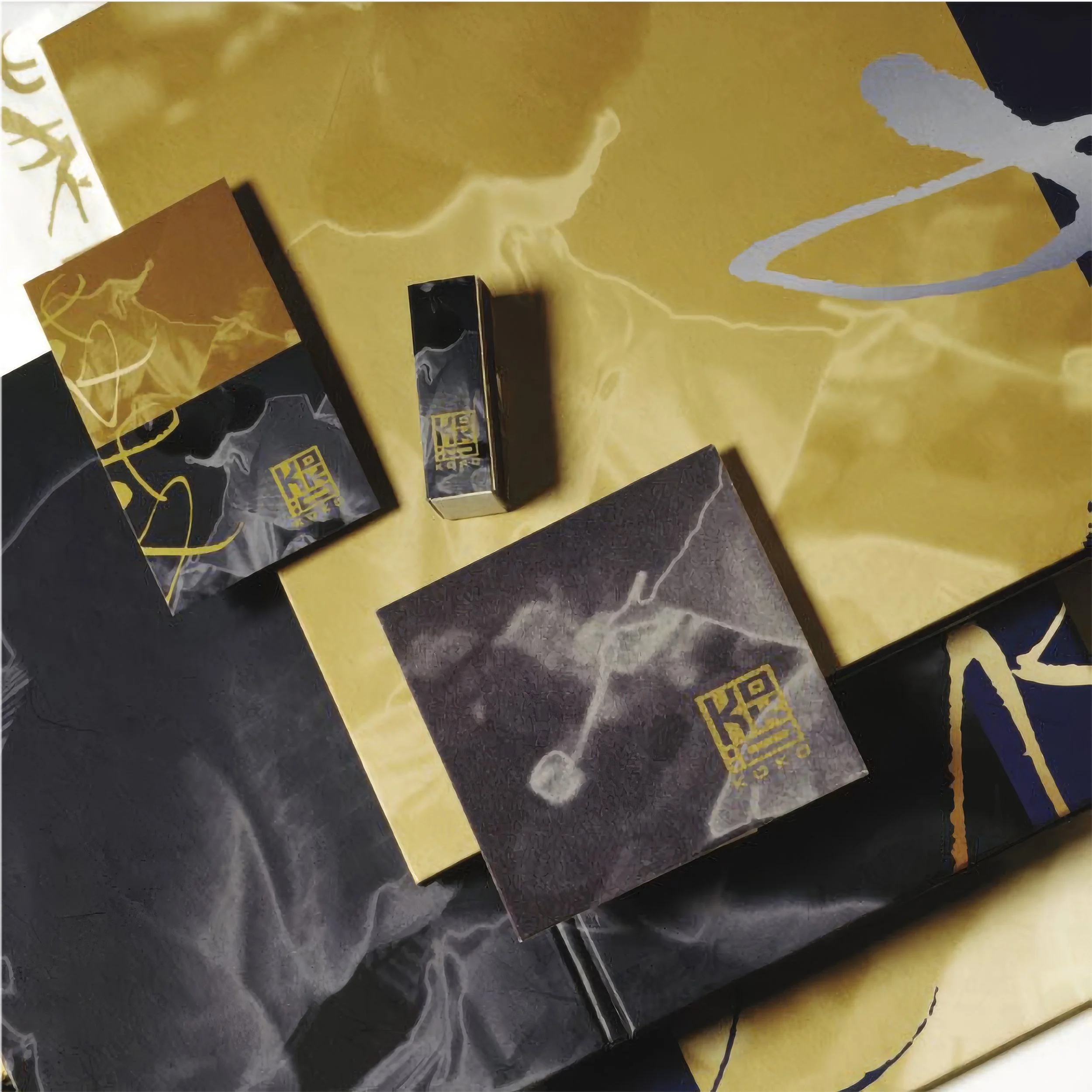 Close-up of black and yellow packaging with abstract gold foil design, possibly candy or snack wrappers, on a dark surface.