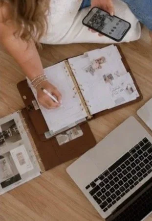 Person planning or working at a desk with a planner, laptop, and smartphone.