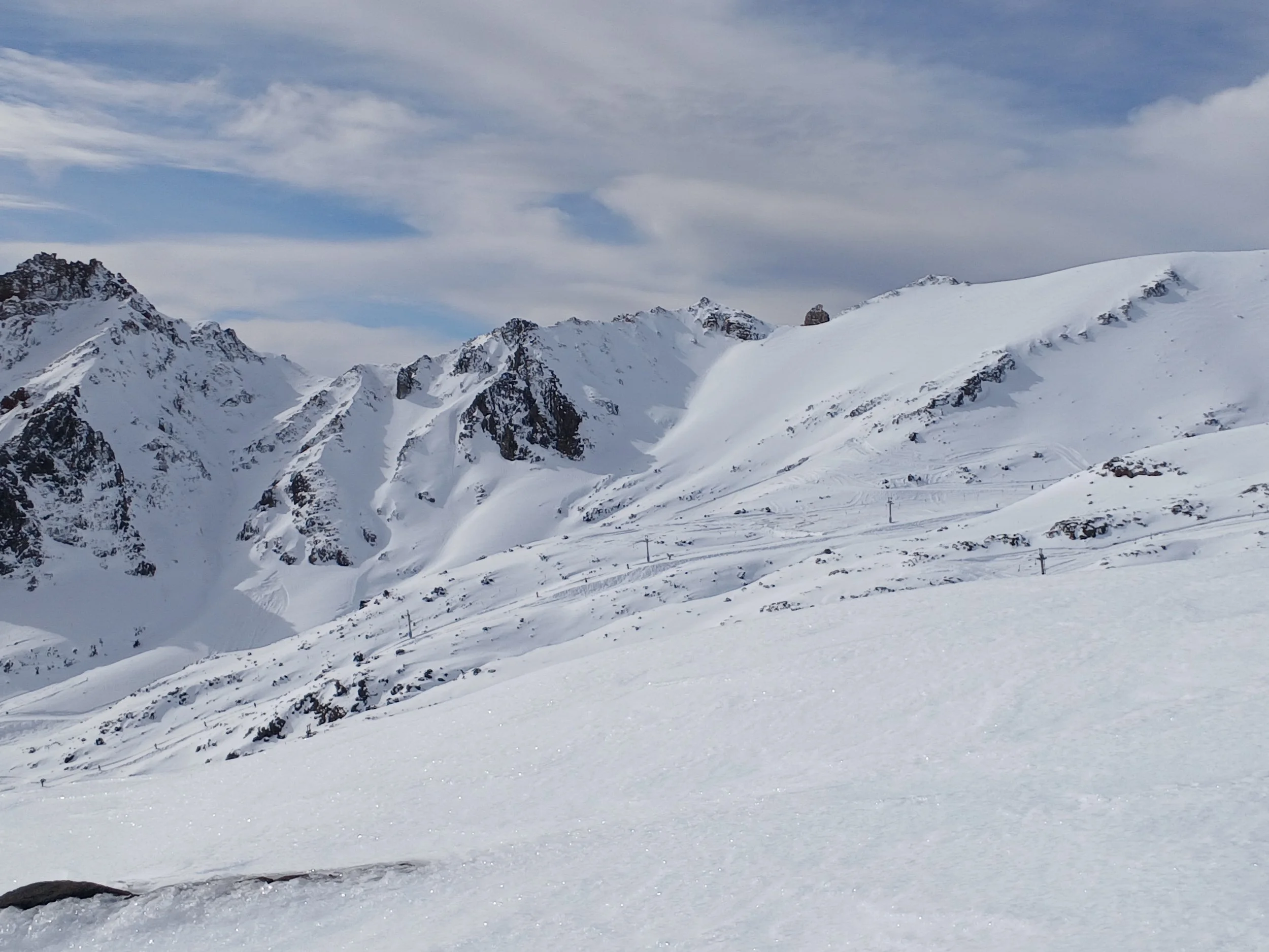 Snow-covered mountain range with sharp peaks under a clear blue sky.