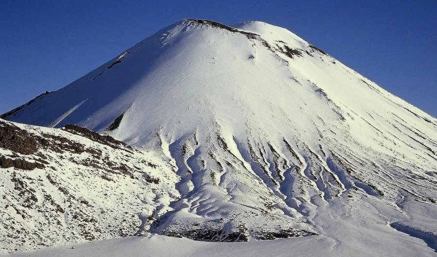 Snow-covered volcanic mountain against a clear blue sky