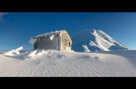 A snow-covered building and a mountain in a winter landscape