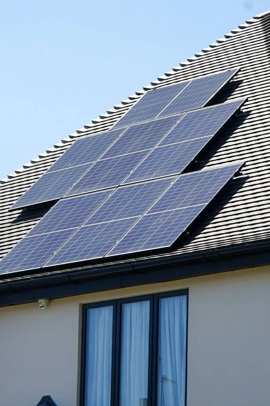Solar panels installed on the roof of a house with a window visible below.