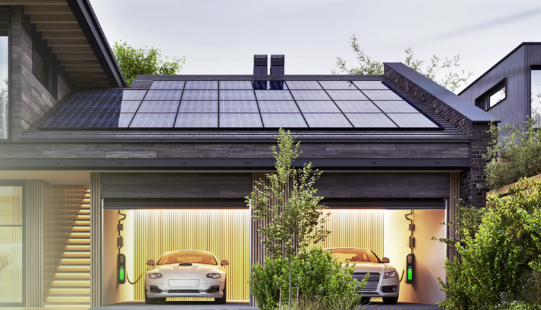 Two white electric cars charging in a garage under a house with solar panels on the roof, surrounded by greenery.