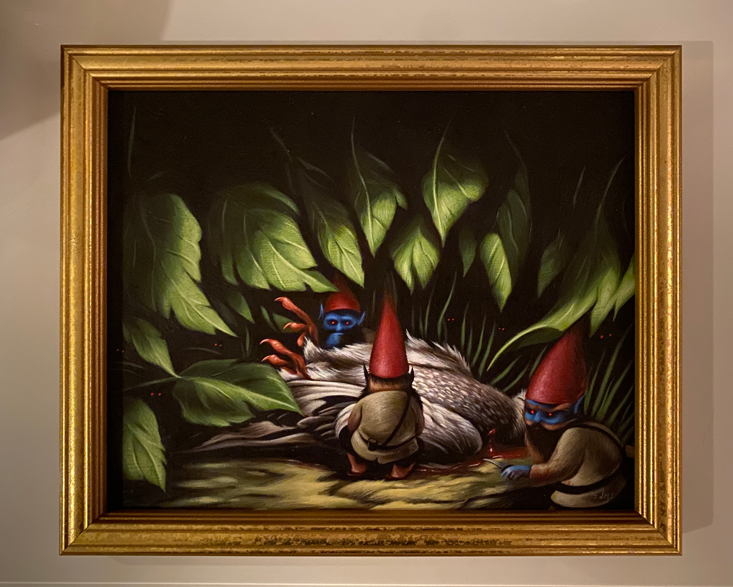Painting of a bird with colorful feathers surrounded by large green leaves in a gold frame.