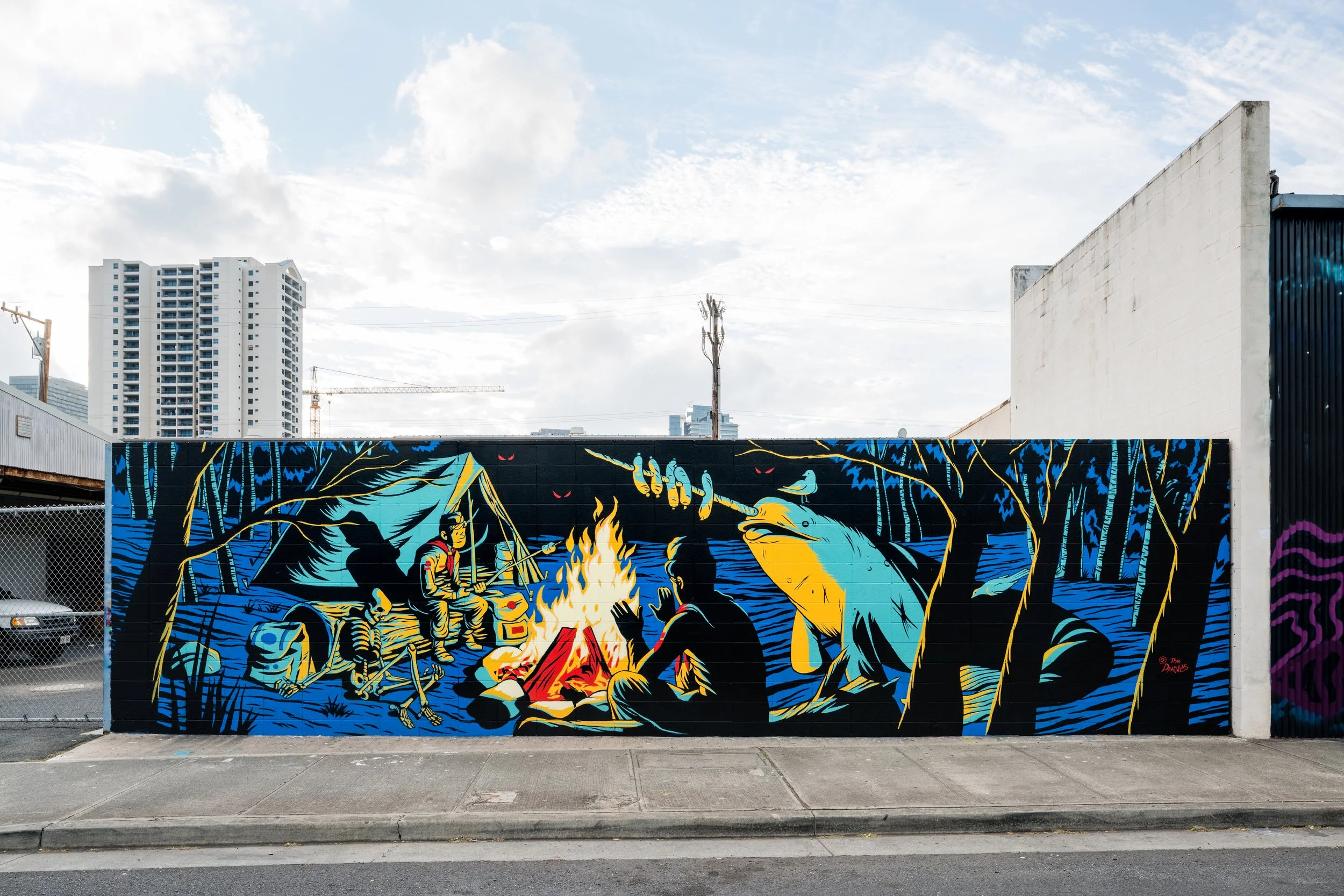 A mural on a wall depicting a scene of people around a campfire with trees and a campfire in a stylized, colorful illustration.