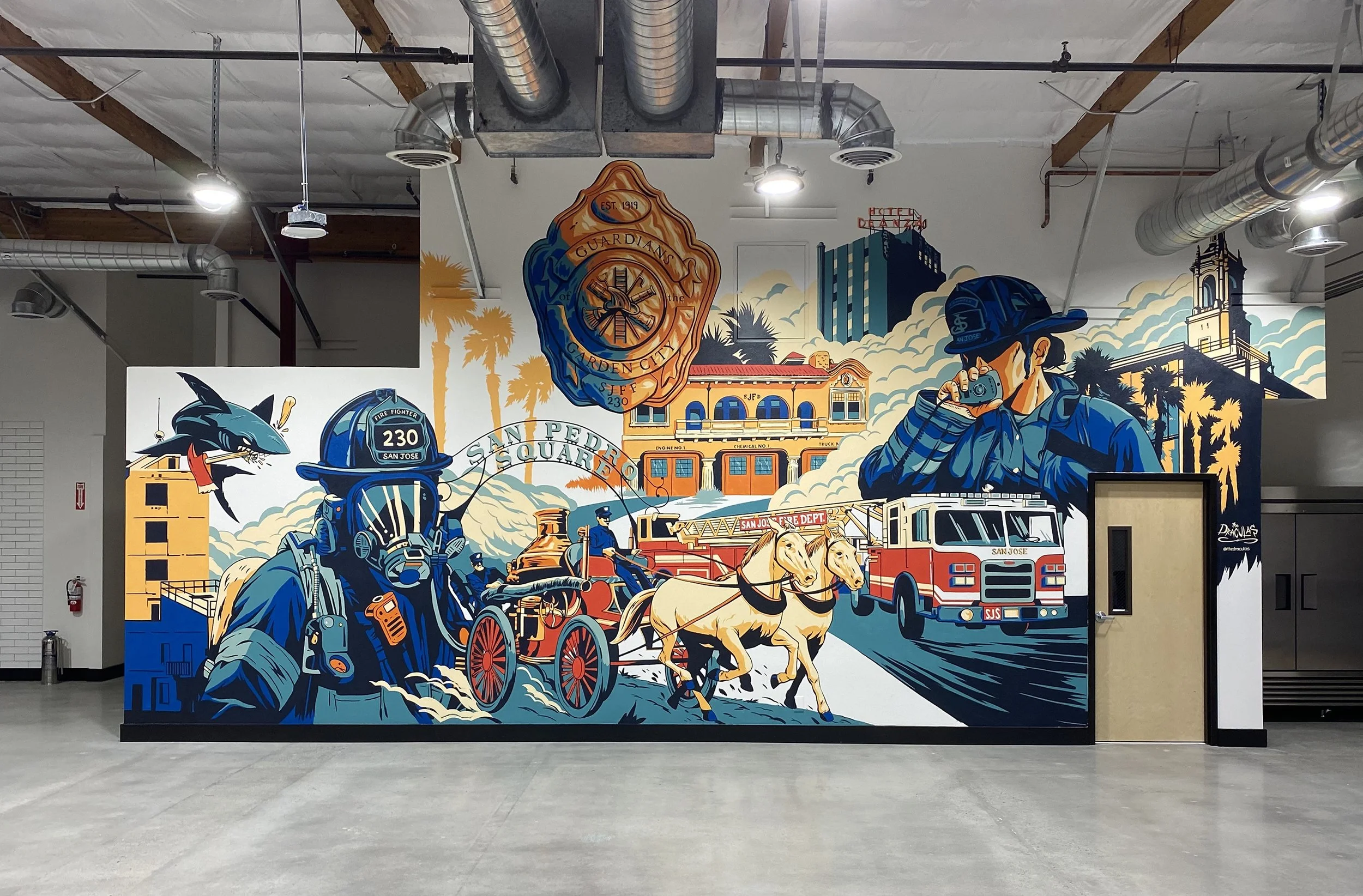 Colorful mural depicting firefighters, fire trucks, a firefighter with a camera, fire department badge, and cityscape elements in an indoor setting.