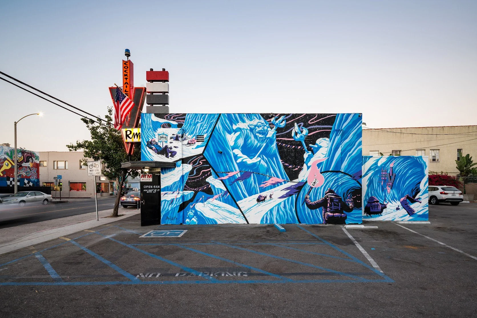 Colorful street mural depicting a large blue wave, two figures with raised fists, rain, and other abstract elements, located on the side of a building in an urban area.