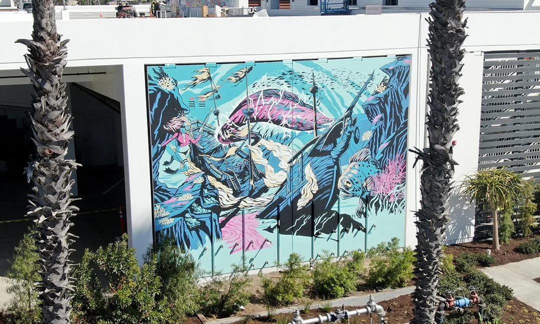 Colorful mural featuring an ocean scene with a large pink fish, a mermaid, a dolphin, and coral, painted on a garage door.