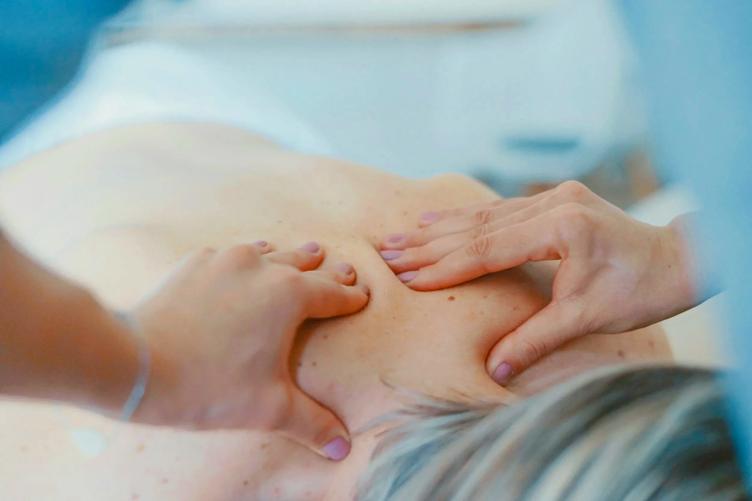 Person receiving a upper back massage in a clinical or setting.