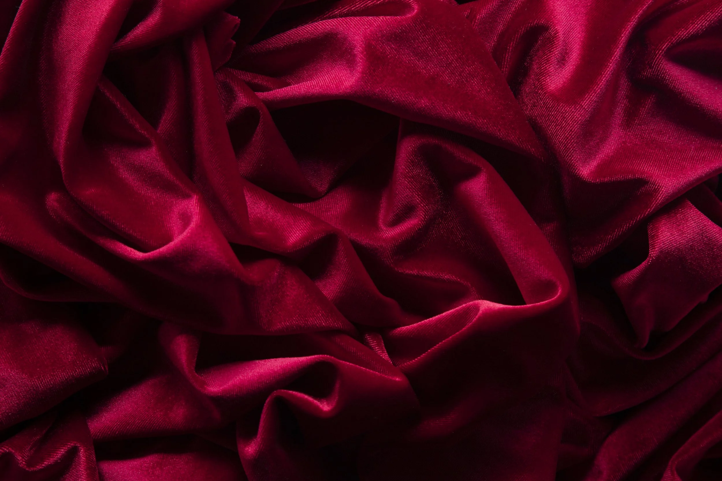 Red velvet fabric with soft folds and a shiny texture.