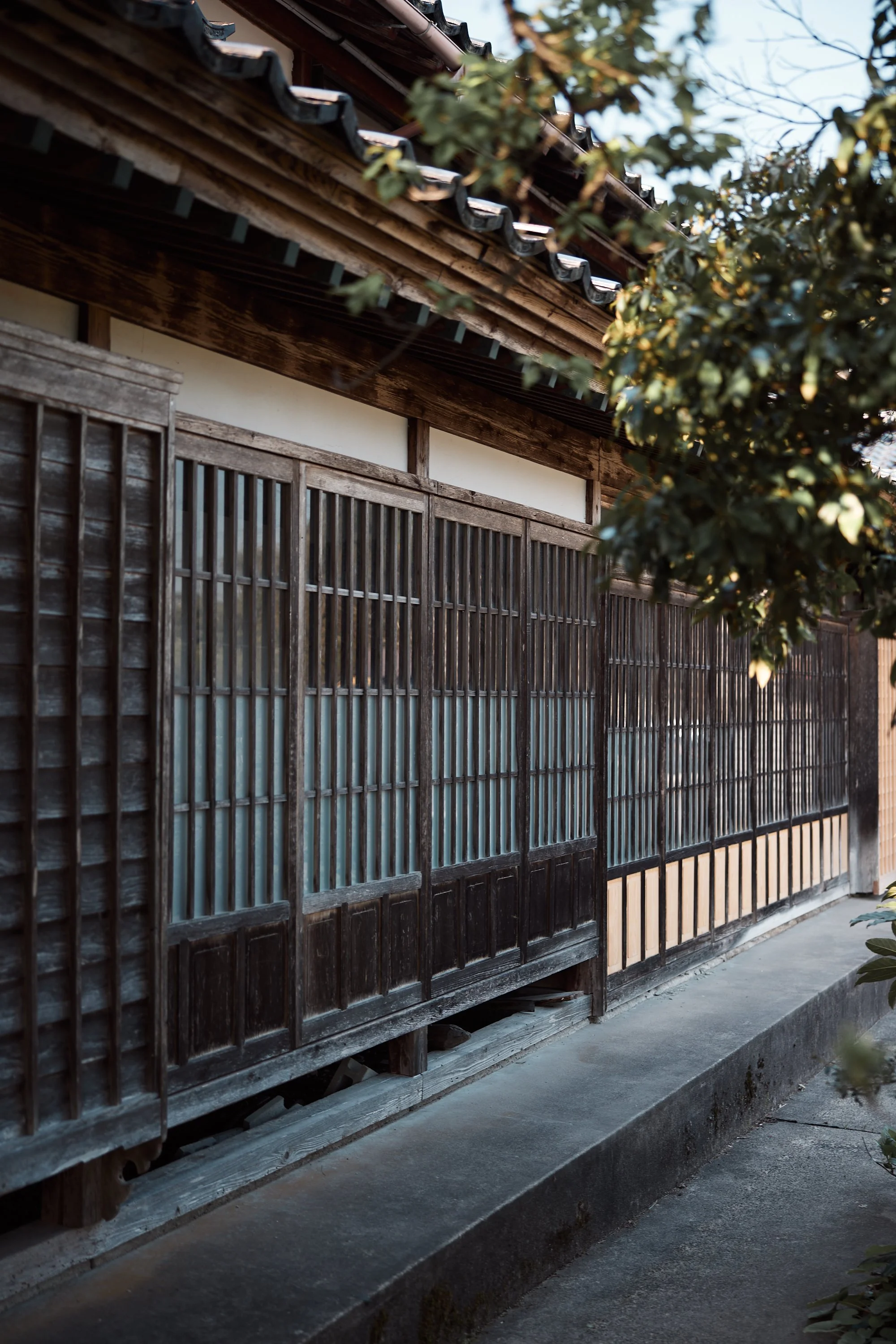古い木製の日本家屋の格子戸と瓦屋根が写っている。