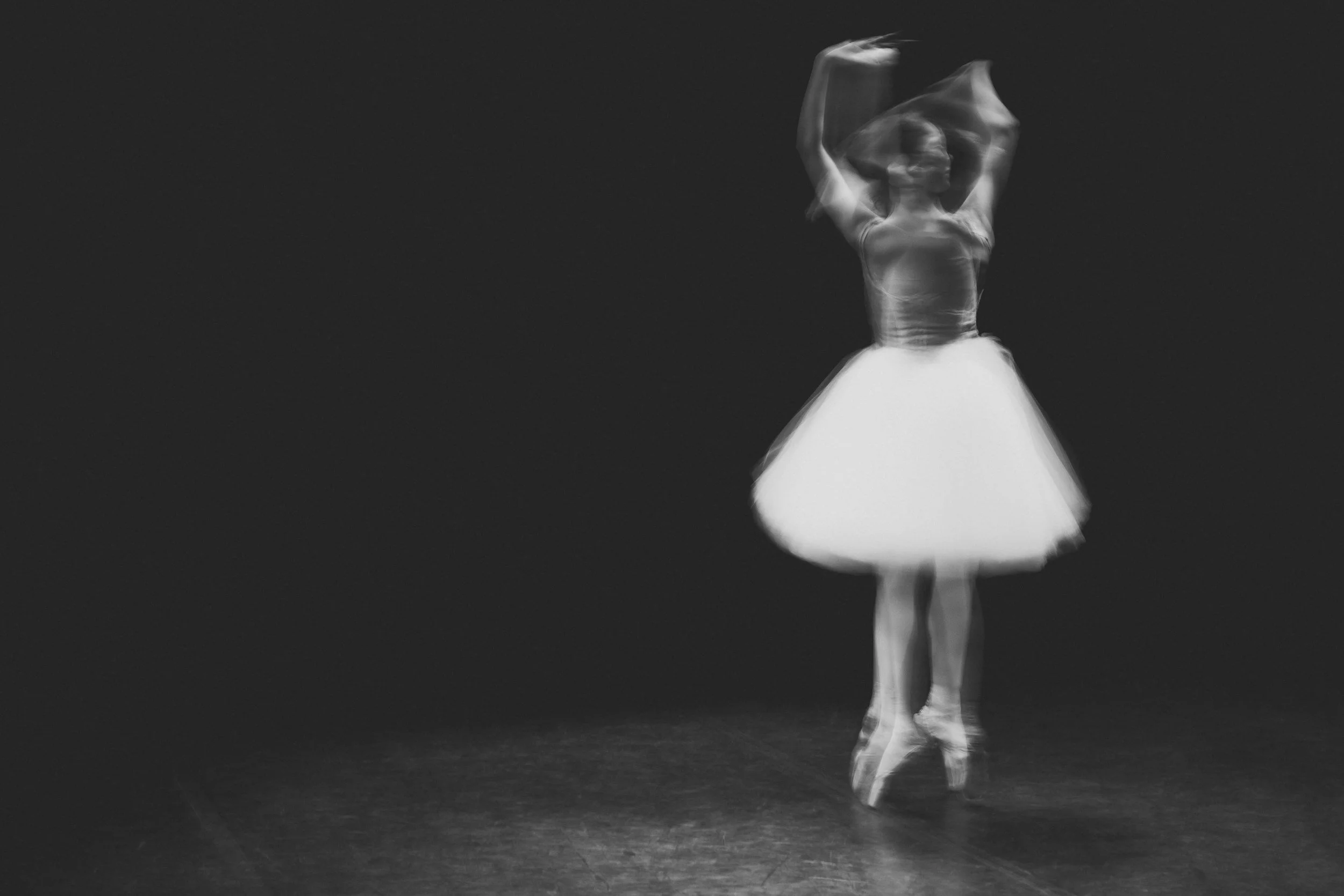 A dancer in a flowing dress is captured in motion on stage, with motion blur indicating graceful movement.