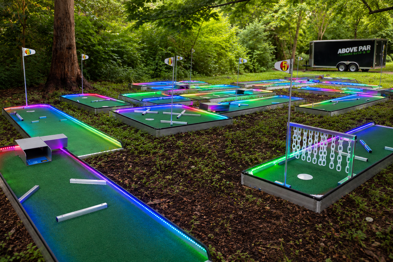 Miniature golf course with multiple holes outlined by colorful neon lights, set outdoors among trees and greenery.