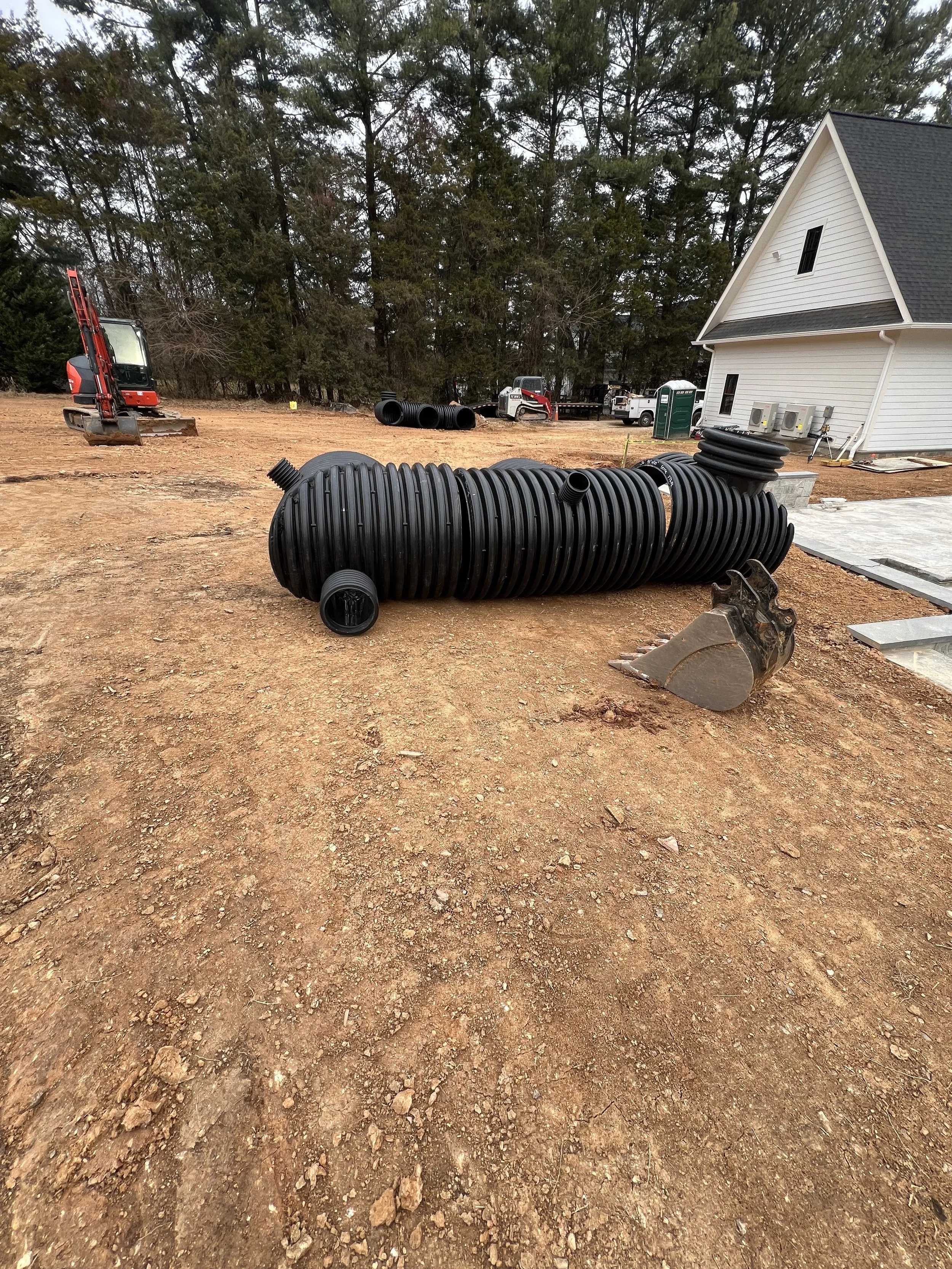 Corrugated HDPE detention pipes set in a trench with a vertical riser and cleanout during underground stormwater detention installation in Northern Virginia.