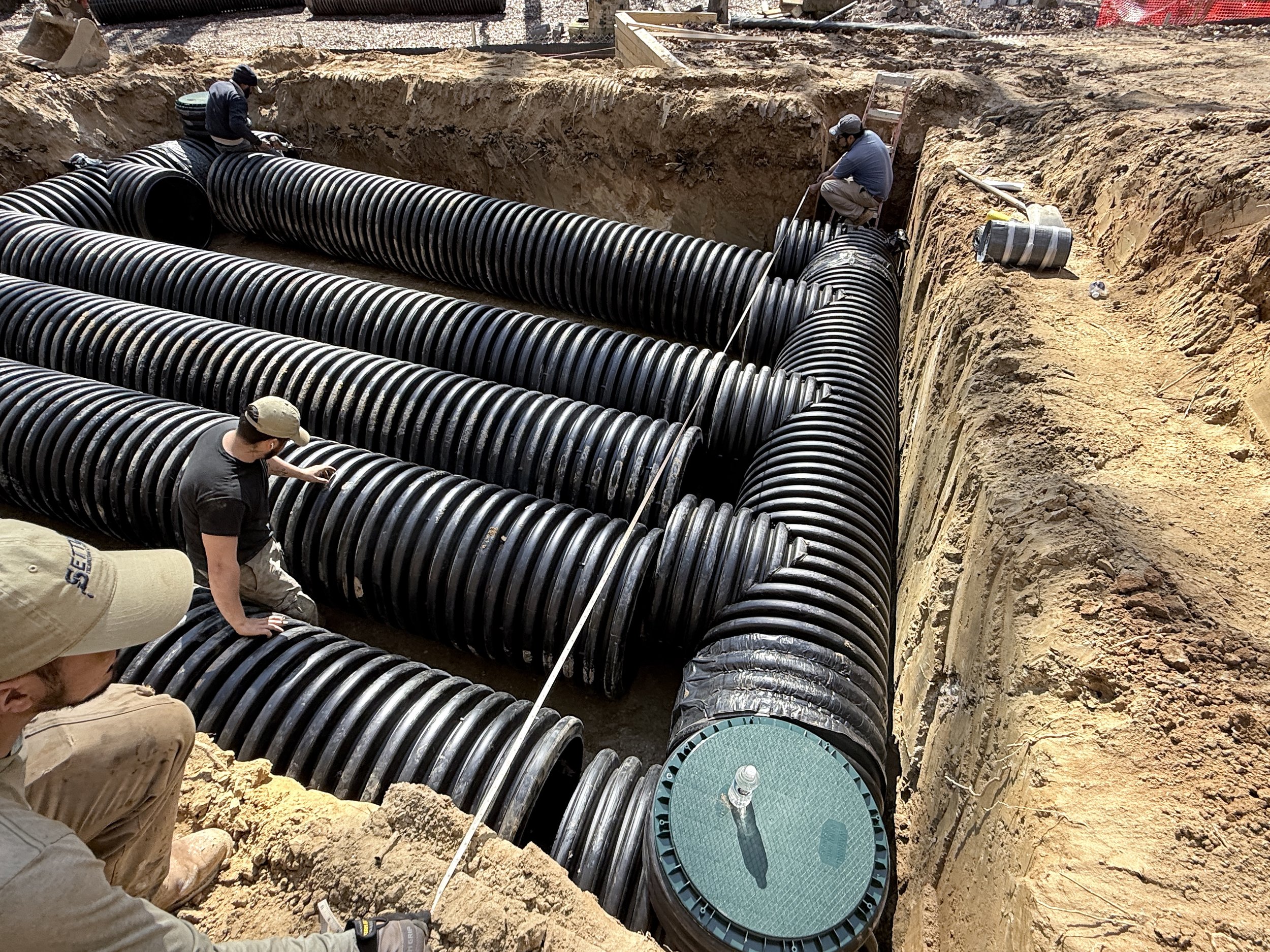 Capital Stormwater crew installing large-diameter HDPE pipe for an underground stormwater detention system in an open trench in Northern Virginia.