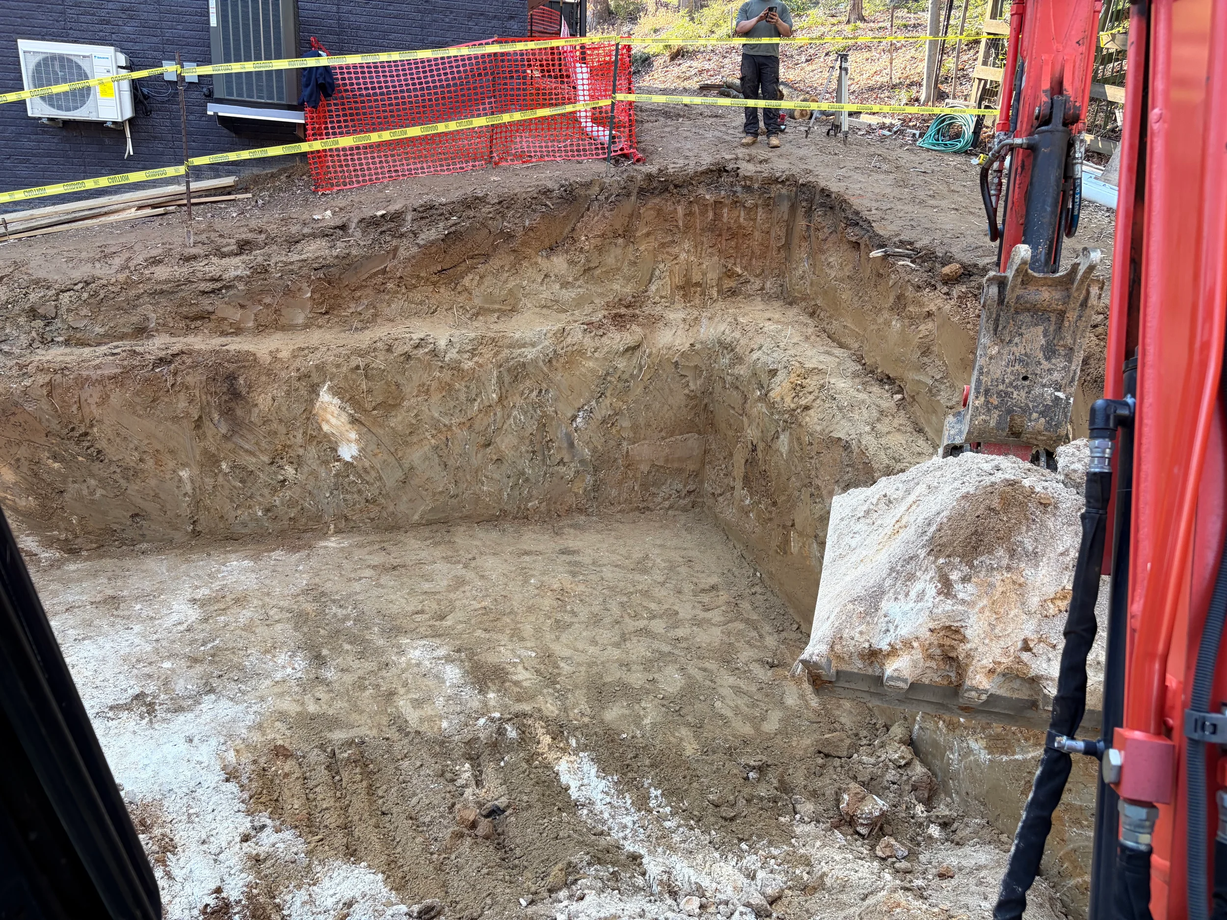 Corrugated stormwater detention tank staged on graded soil with excavator and open construction area ready for underground BMP installation.