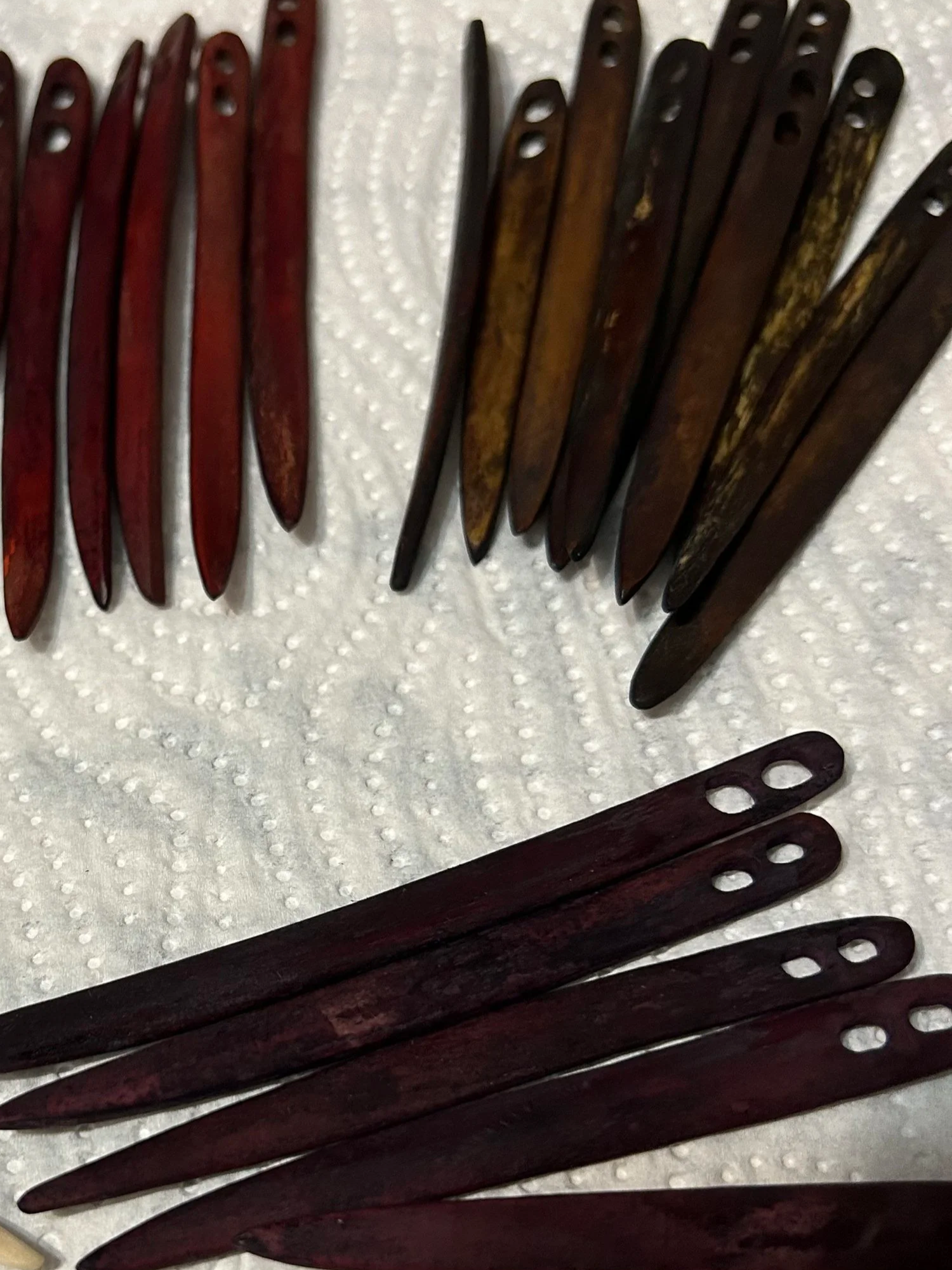 A collection of wooden nalbinding needles made of reindeer bone arranged on a white textured surface, with some combs overlapping each other.