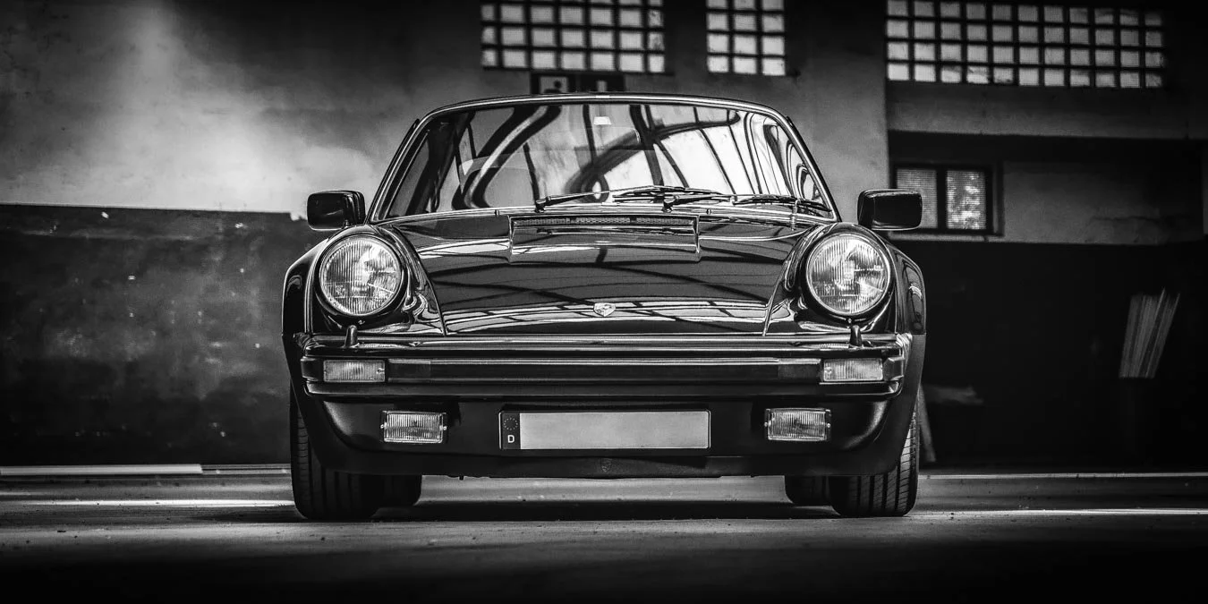 Schwarzer Oldtimer im Schwarz-Weiß-Foto vor dunklem Hintergrund in einer Garage