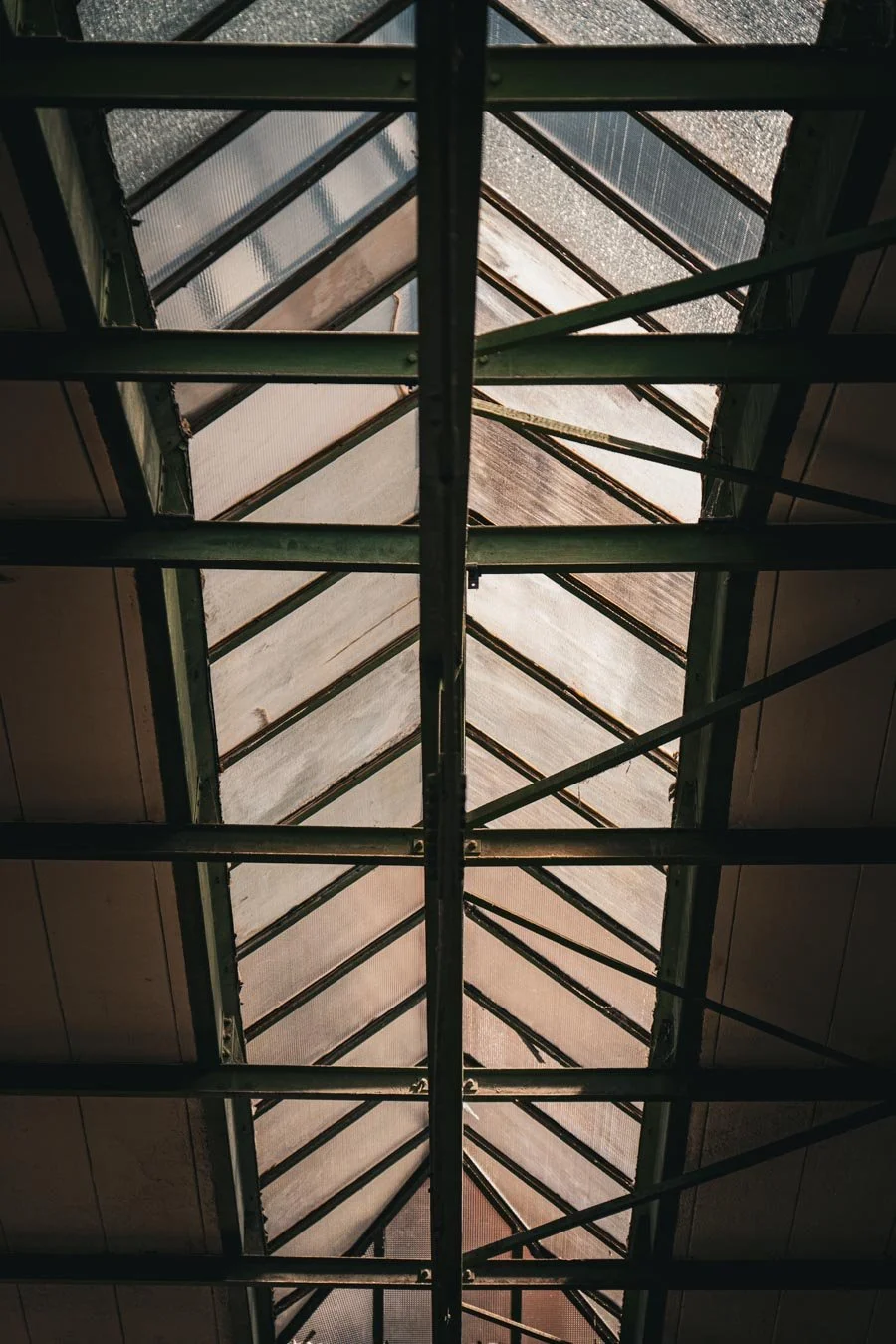 Blick durch ein Dachfenster mit einem Metallrahmen und Glasplatten, die Licht durchlassen.