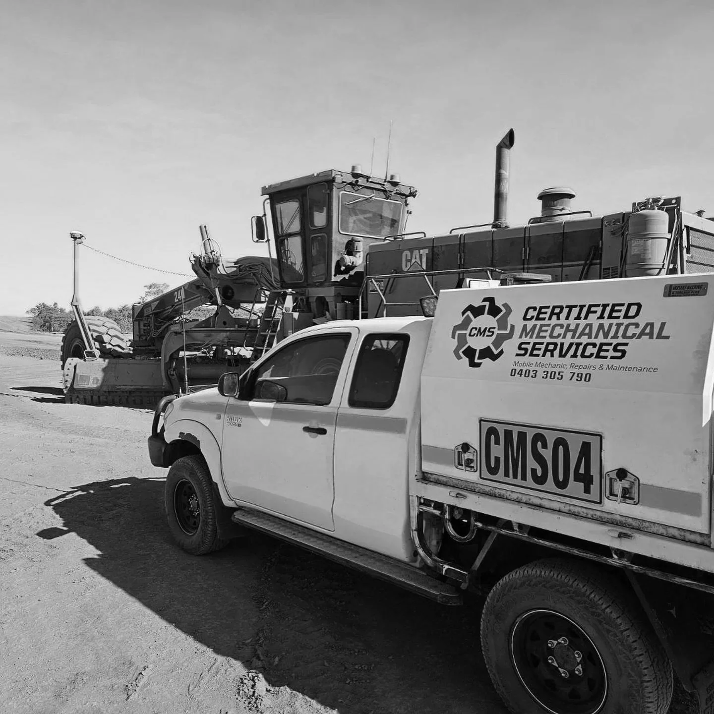 A certified mechanical services truck parked on a dirt road with a large bulldozer in the background.